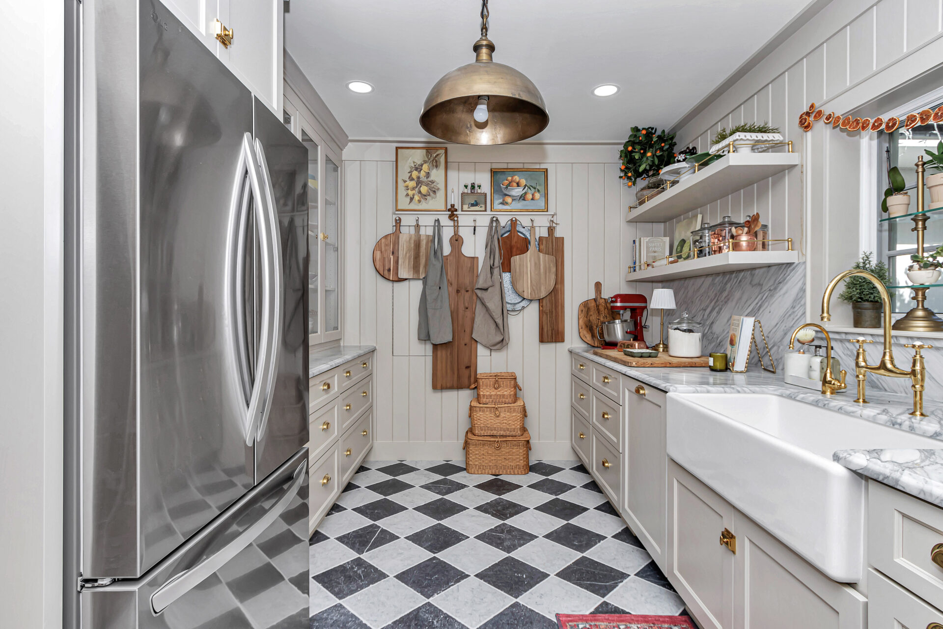 A beautifully designed kitchen featuring stainless steel appliances, marble countertops, wooden cutting boards, and chic decorative elements. The space showcases a harmonious blend of modern and farmhouse aesthetics.