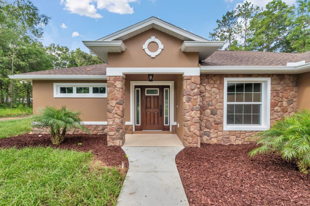 Entrance detail featuring custom fieldstone wainscoting and cherry wood door in Ocala.