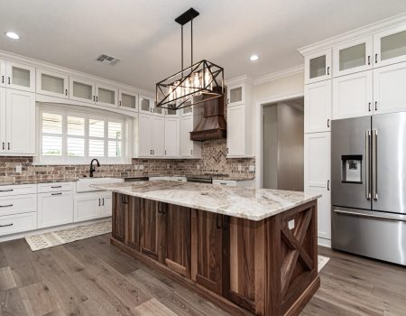 Large kitchen with granite counter tops, brick back splash and custom cabinetry around the large double door fridge - New Construction Homes