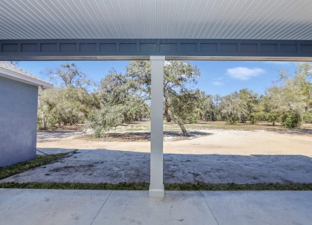 A peaceful perspective of the cleared homesite and surrounding natural Florida woodlands from the rear porch