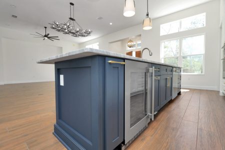 Bold blue kitchen island with a built-in wine fridge and dishwasher, topped with white and grey granite.