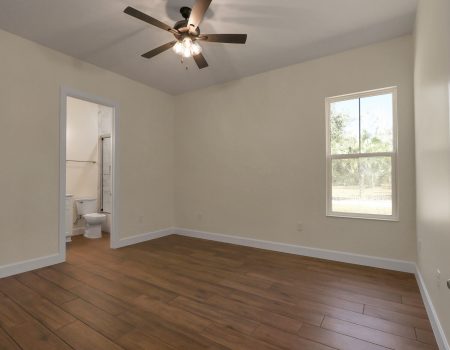 Bright third bedroom featuring a large single-pane window and a private en-suite bathroom entrance.