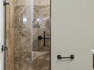 Close-up of the tall, modern glass shower door in the guest bathroom of this Ocala custom home