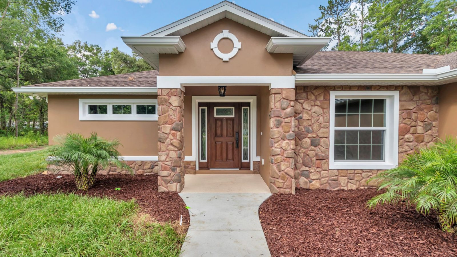Entrance detail featuring custom fieldstone wainscoting and cherry wood door in Ocala.