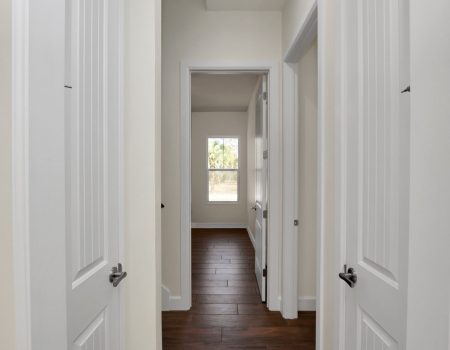 Functional hallway layout showcasing matching white-paneled closet doors on either side, providing ample linen storage.