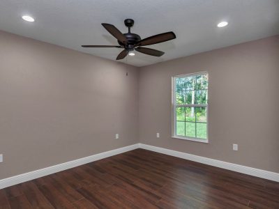 Guest bedroom two in Ocala custom home, featuring clean lines and wood-look tile flooring
