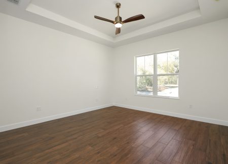 Spacious master bedroom with trey ceilings and wood-look tile, designed by Jason Boutwell Construction, a premier custom home builder in Ocala, FL.