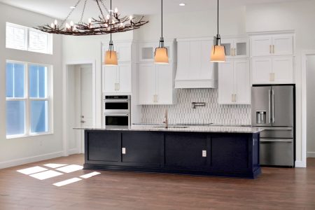 Gourmet custom kitchen with white cabinetry, a blue center island, and an arched mosaic backsplash, showcasing the high-end finishes from Jason Boutwell Construction, a trusted custom home builder in Ocala, FL.