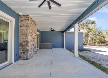 Rear exterior view showcasing the multicolor stone fireplace structure integrated into the bold blue walls of the luxury lanai.