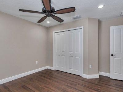 Spacious guest bedroom in Ocala custom home featuring wood-look tile flooring and ample closet space