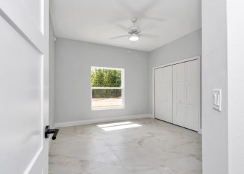Entry to bedroom #2 with luxury tile flooring ceiling fan and closet